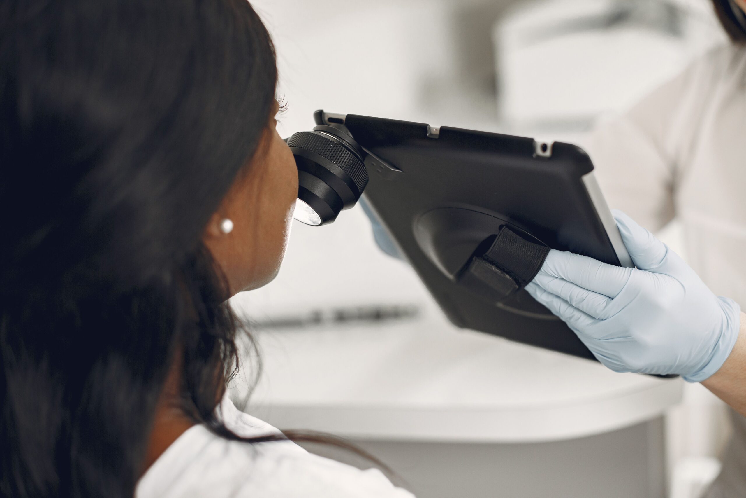 Dermatologist examining patient skin with a digital dermatoscope and tablet