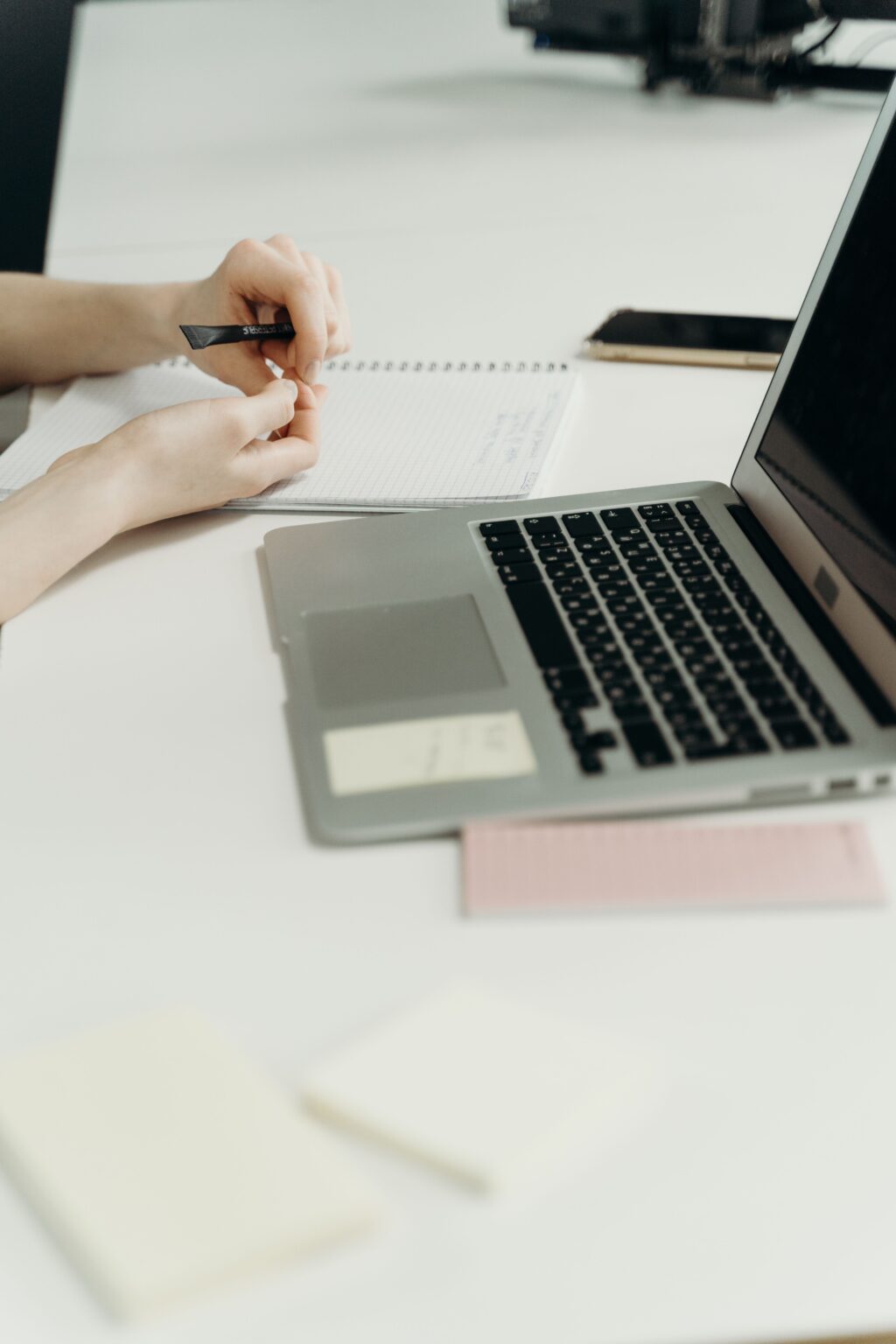 Hands planning in a notebook beside an open laptop