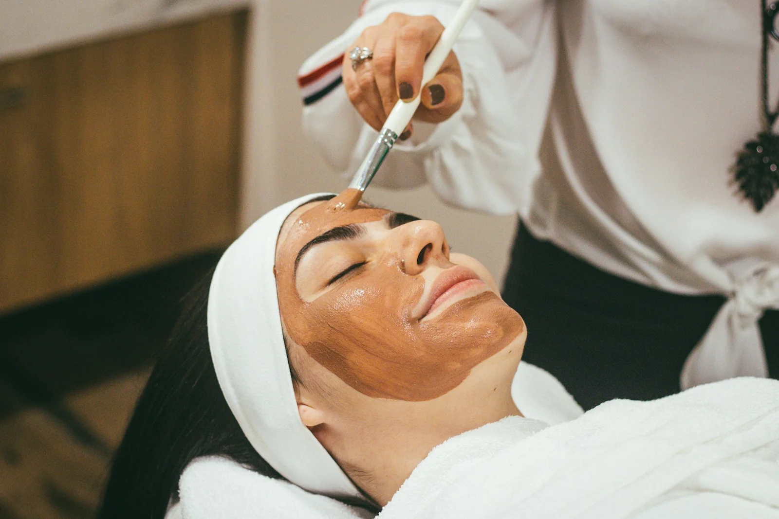 A facial mask being applied with a brush during a skin treatment